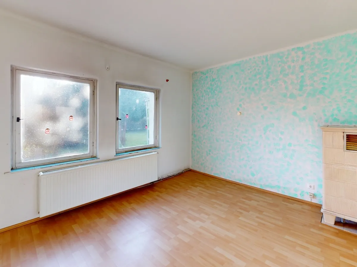 Wohnraum im Bestand: gemusterte Tapete, alter Kachelofen, Laminat